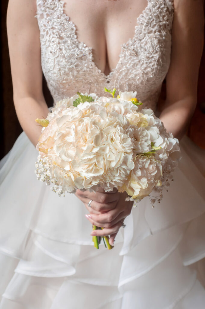 Closeup shot of bride in white lace dress holding a bouquet