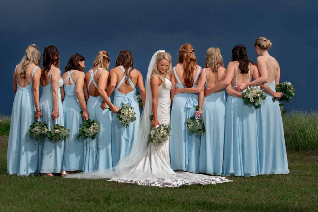 Rear view photo of bride in the middle of a line with bridesmaids in light blue dresses on either side of her