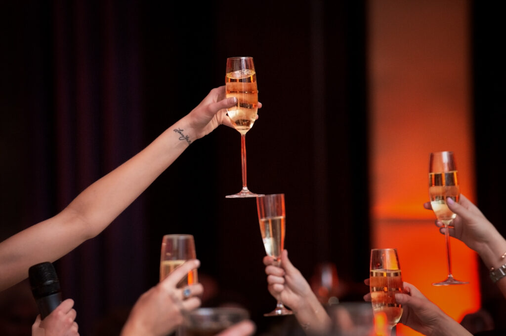 Close up view of guests' hands holding up champagne glasses for a toast