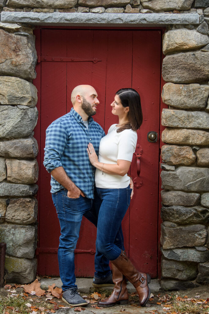 A couple hugs one another in front of a red door.