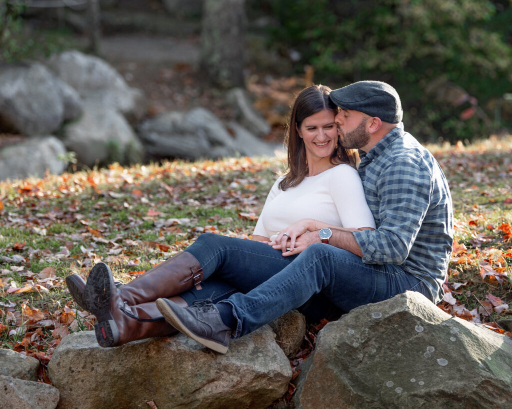 A couple sits on rocks outdoors in fall.