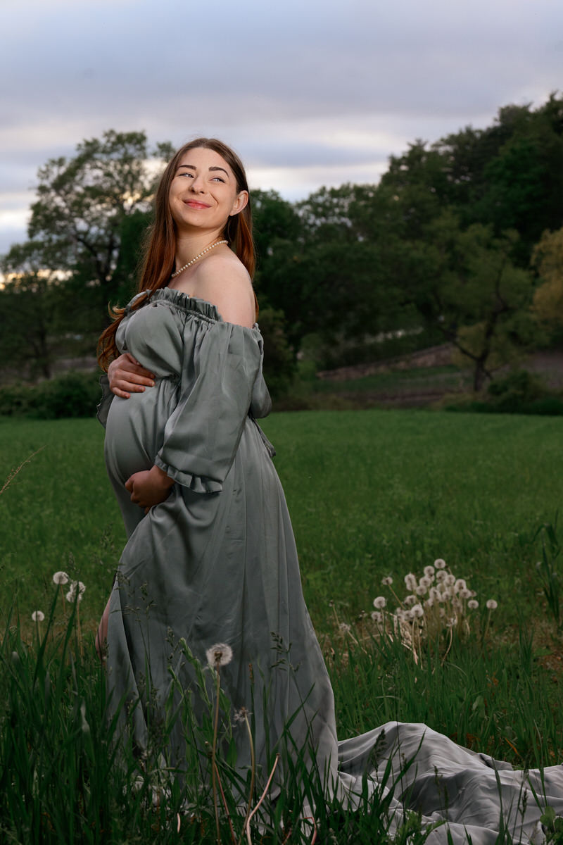 A woman smiling over her shoulder while holding her pregnant stomach