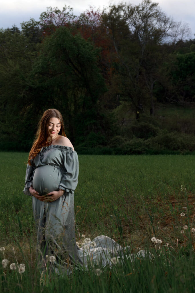 A woman with her hands under her pregnant stomach 