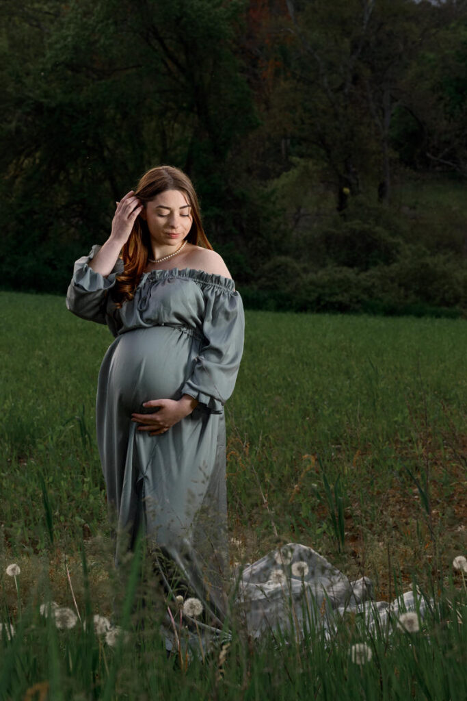 A pregnant woman with one hand under her stomach and the other in her hair 