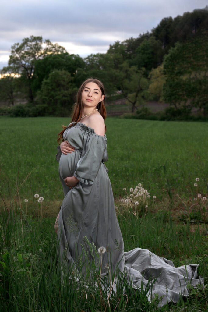 A pregnant woman smiling while holding her baby bump 