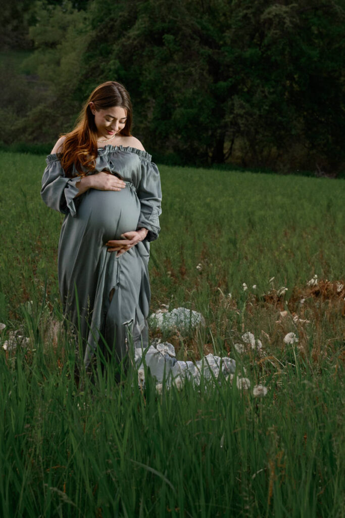 A pregnant woman smiling down at her stomach 