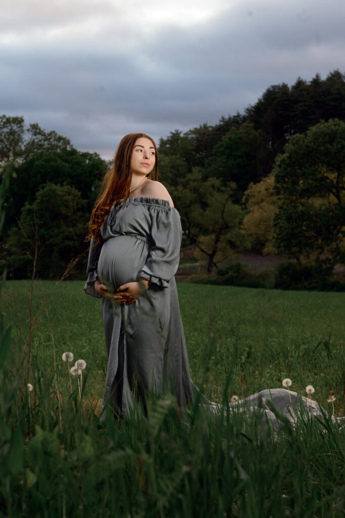 A pregnant woman holding her stomach and looking off to the side 